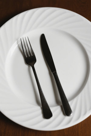 Knife and fork cutlery on a white dinner plateの素材