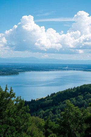 Lake and forest landscape under blue sky and white cloudsの素材