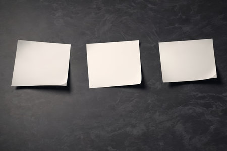 Three blank sticky notes on a black backgroundの素材