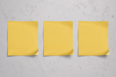Three yellow sticky notes on a white backgroundの素材