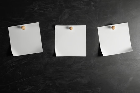 White paper with thumbtacks on black backgroundの素材