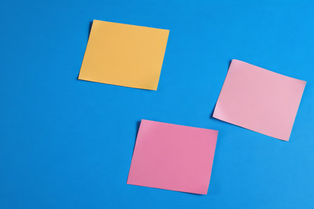 Colored blank sticky notes on a blue backgroundの素材