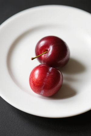 Two red fresh cherries on a white plateの素材