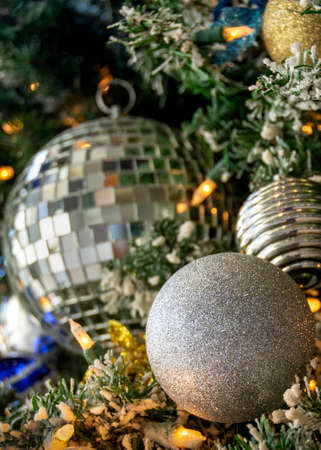 Silver Christmas ornaments hanging from an illuminated Christmas tree. Suitable background for a...