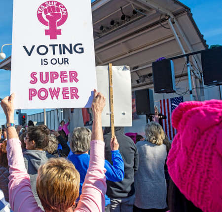 Santa Ana, CA / USA - Jan 18, 2020: A woman holds a âVoting Is Our Super Powerâ Woman Power sign at the OC Womenâs March. U.S. Representative (D) Katie Porter is onstage in the background.のeditorial素材