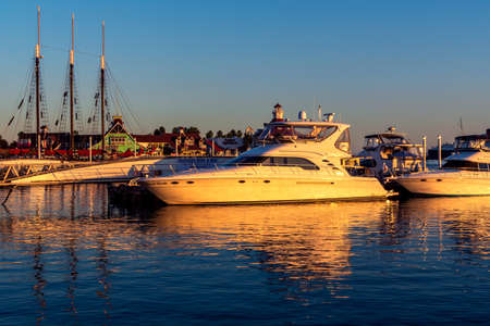 Long Beach, CA / USA - October 13, 2020: Boats docked at Rainbow Harbor at Shoreline Village at sunset, with restaurants and shops in the background.のeditorial素材
