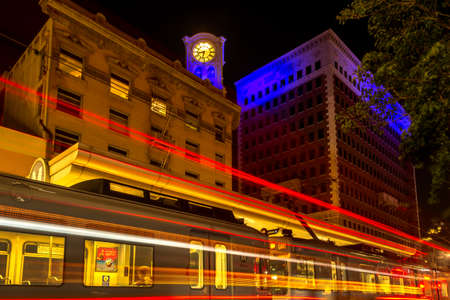 Long Beach, CA / USA - Oct 20, 2020: Night cityscape of downtown Long Beach's modern Metro train station, light trails and 1907 distinctive, historical clock tower with six-foot-diameter clock face.のeditorial素材