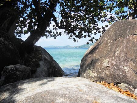 tropical beach 11, view of beautiful tropical beach between large rocks, with a tree   Phuket, Thailand, Asia の写真素材