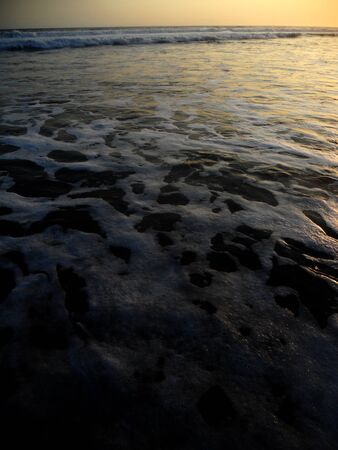 Black sand and surf sunsetの写真素材