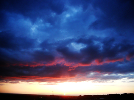Beautiful and dramatic sunset with reds reflected on dramatic cloud formationsの写真素材