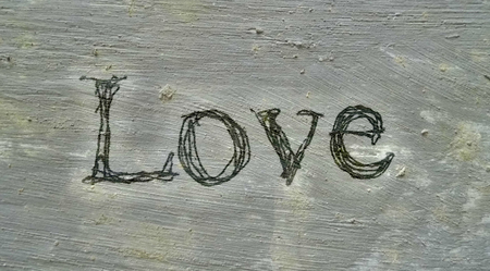 love hand-written, the word love written by hand, artistic word love, dark scribbled lettering with added fibrous texture and faint pale border, on painted concrete texture.の写真素材