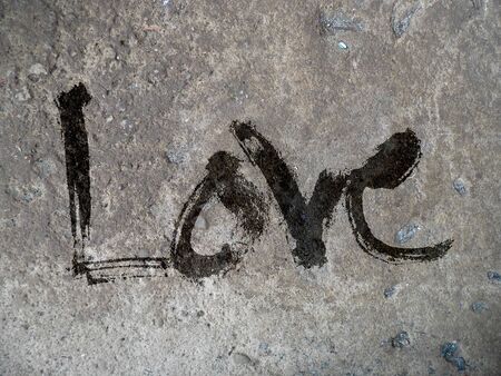 love hand-written, the word love written by hand, artistic word love, painted roughly with split brush lettering, gray on rough concrete texture.の写真素材