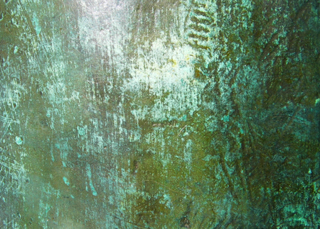 A bold textural surface, shiny distressed bronze sculpture surface with patina, scratches and turquoise, green and yellow tints.の写真素材