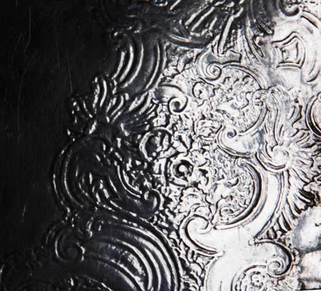 Surface detail of a old silver object with embossed detail of curlicues and texture.の写真素材