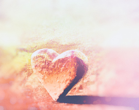 Painted red and orange 3D heart model with subtle organic bumpy surface texture, lit from the side, with shadow, with vignette blur.の写真素材