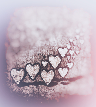 Grunge sketch swirl of many 3D hearts, group of different sized heart shapes in a curved shape, with shadows, on a grunge texture background with pale blur vignette, warm color tints.の写真素材