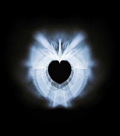 Processed Fractal heart, a beautiful symmetrical fractal with zoom blur, creating a small heart-shaped negative space, pale grays with blue tints on black background, with blur vignette.の写真素材
