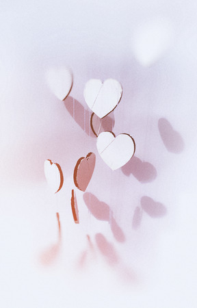 Hanging heart shapes, top-down angled view a group of small hearts hanging at different heights on...