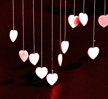 Glitter hearts, a group of hearts covered with silver glitter, hanging from threads, dark background...