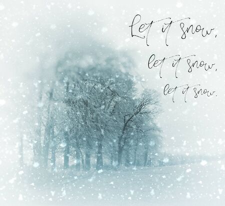 Christmas card with a snowy winter landscape with beech trees, the words Let It Snow, Let It Snow, Let It Snow, vignette blur, yellow and blue tints.の写真素材