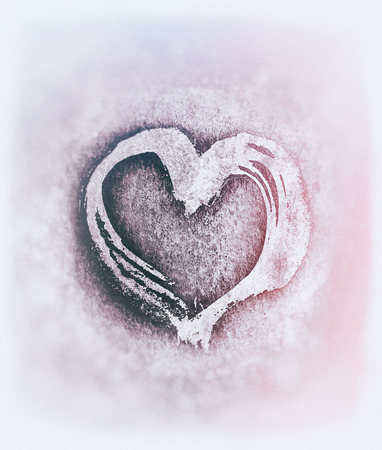 Rough painted heart shape on a rough surface. Pale blurred background. Purple tints.の写真素材