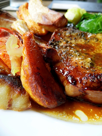 Roast pork dinner with meat and vegetables, on a plate on a table, closeup.の写真素材