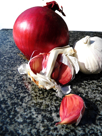 Red onion and garlic on a chopping board.の写真素材