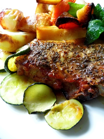 Roast pork dinner with meat and vegetables, on a plate on a table, closeup.の写真素材
