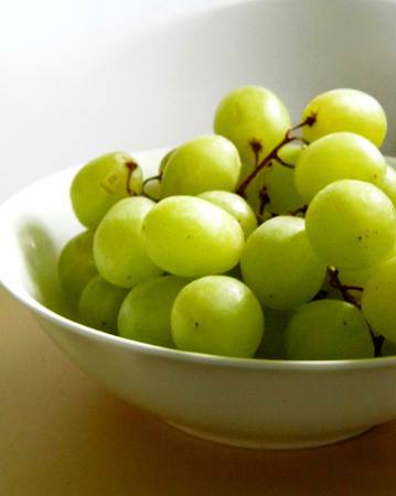 White grapes in a small ceramic bowl, with water drops.の写真素材
