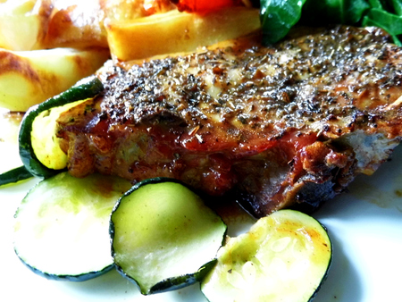 Roast pork dinner with meat and vegetables, on a plate on a table, closeup.の写真素材