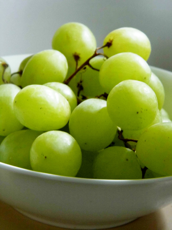 White grapes in a small ceramic bowl, with water drops.の写真素材