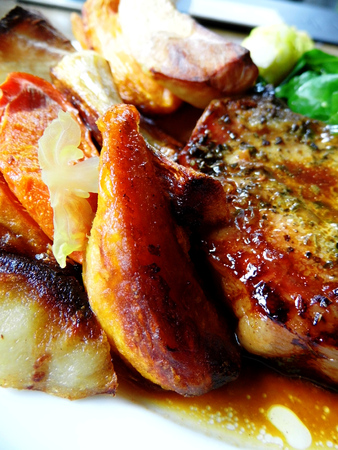 Roast pork dinner with meat and vegetables, on a plate on a table, closeup.の写真素材