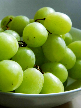 White grapes in a small ceramic bowl, with water drops, closeup.の写真素材