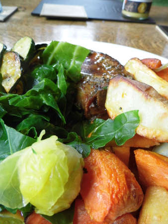 Roast pork dinner with meat and vegetables, on a plate on a table, closeup.の写真素材