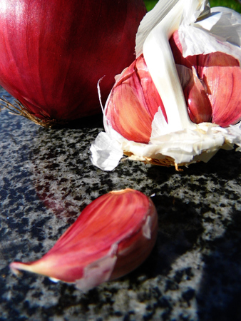 Red onion and garlic on a chopping board.の写真素材