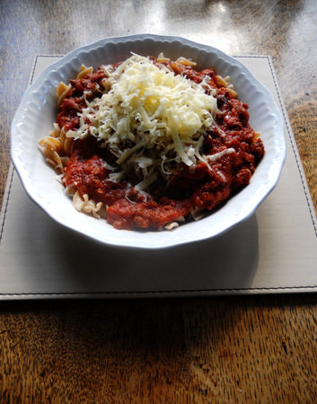Pasta Bolognese with cheese in a white ceramic bowl on a table..の写真素材