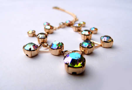 Gold bracelet with colored glass closeup, on a flat surface.の写真素材