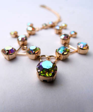 Gold bracelet with colored glass closeup, on a flat surface.の写真素材