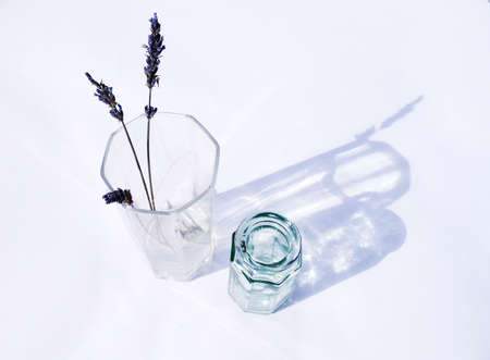 Dried lavender in a sunlit glass vase with a smaller vase beside.の写真素材