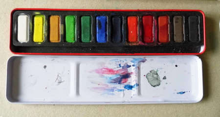 Side view of a used box of watercolor paints, with inside of lid.の写真素材