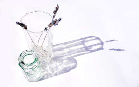 Dried lavender in a sunlit glass vase with a smaller vase beside.の写真素材