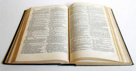 Old book lying open on a surface, lit from the side with shadow.の写真素材