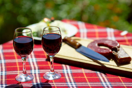 Glasses of red wine on a table, some flowers in the backgroundの写真素材