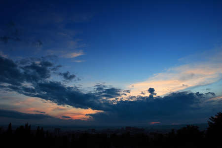 Sunset with blue sky, dark clouds and some orange colorsの写真素材