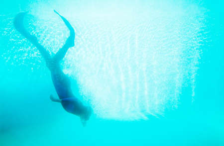 Scuba diver plunging in deep blue waterの写真素材