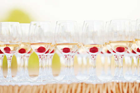 Multiple party glasses with alcohol drink and red cherry on table