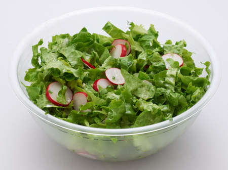 Green lettuce and red radish salad in transparent plastic cup on whiteの写真素材