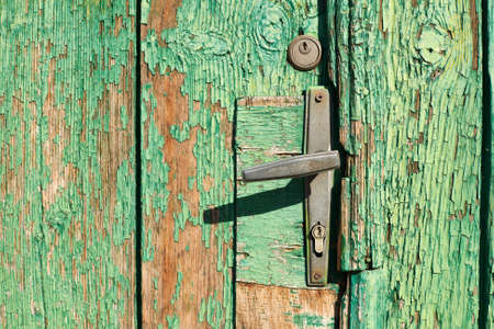 Old door handle on wooden door background with green ckracked paint の写真素材