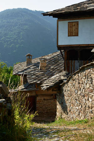 Street with old houses in Kovatchevitsa village, with the Rhodope mountain, Bulgariaの写真素材