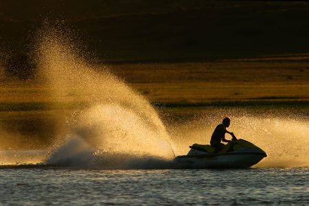 Backlit jet ski water spray, late afternoonの写真素材